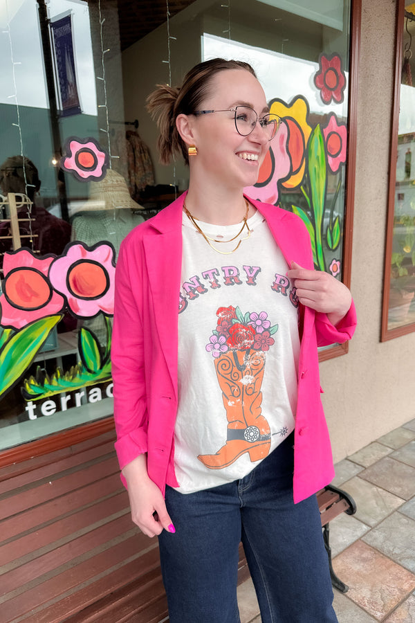 Woman wearing a pink blazer over a graphic tee shirt with denim.