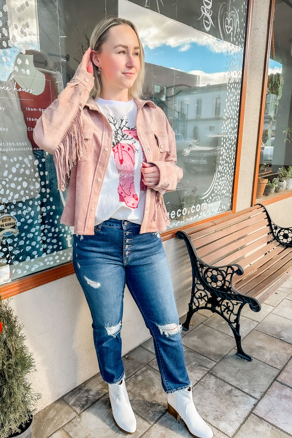 girl wearing a Mauve Suede Fringe Jacket over a cowgirl tee with jeans and white boots