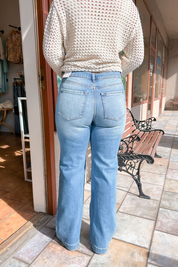 Rear view of a girl wearing a pair of medium wash vintage slim wide leg jeans with an off white button sweater.